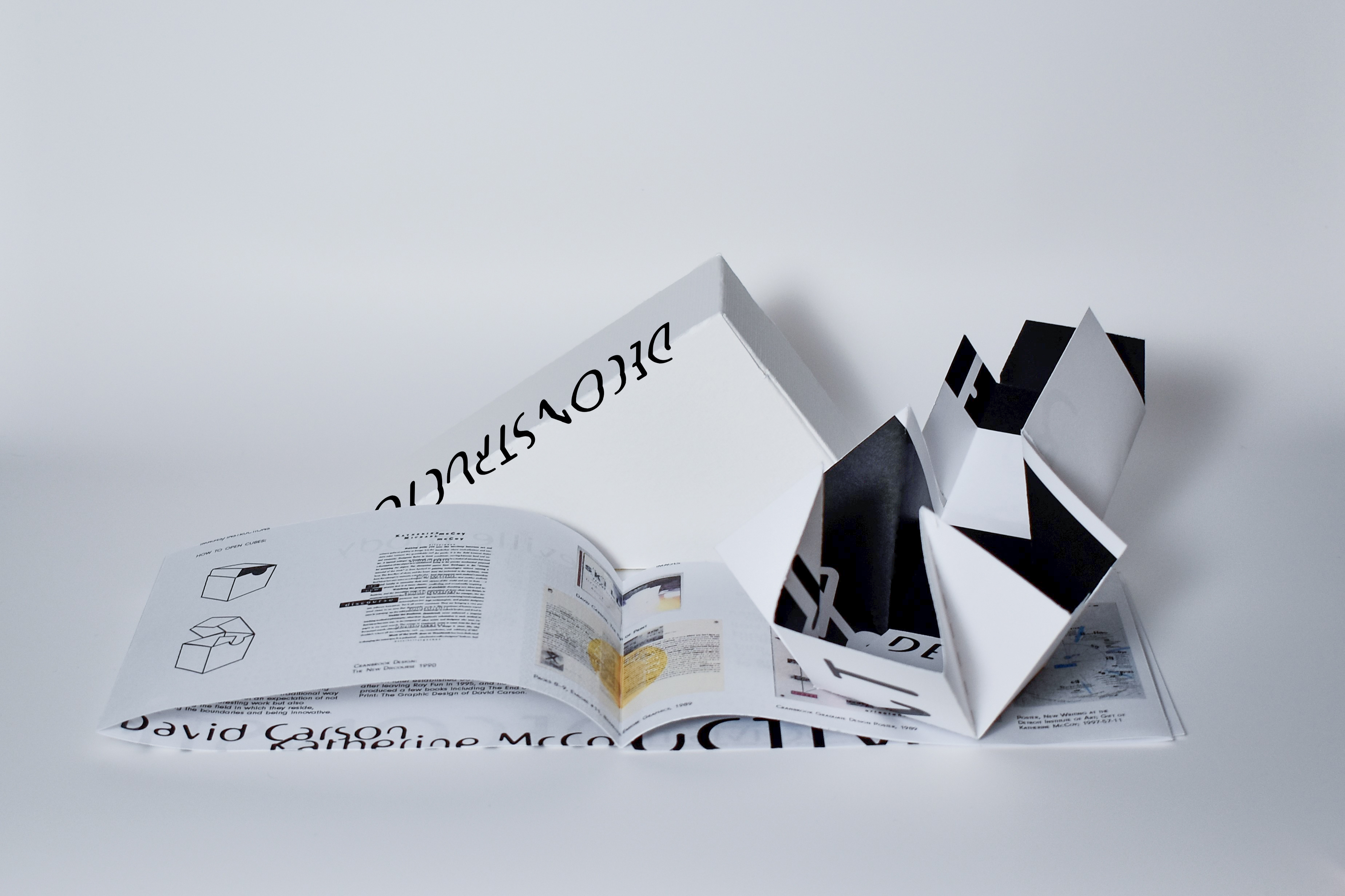 Open game piece on top of the booklet, opened to the instructions and images section. Outside game box is behind both.